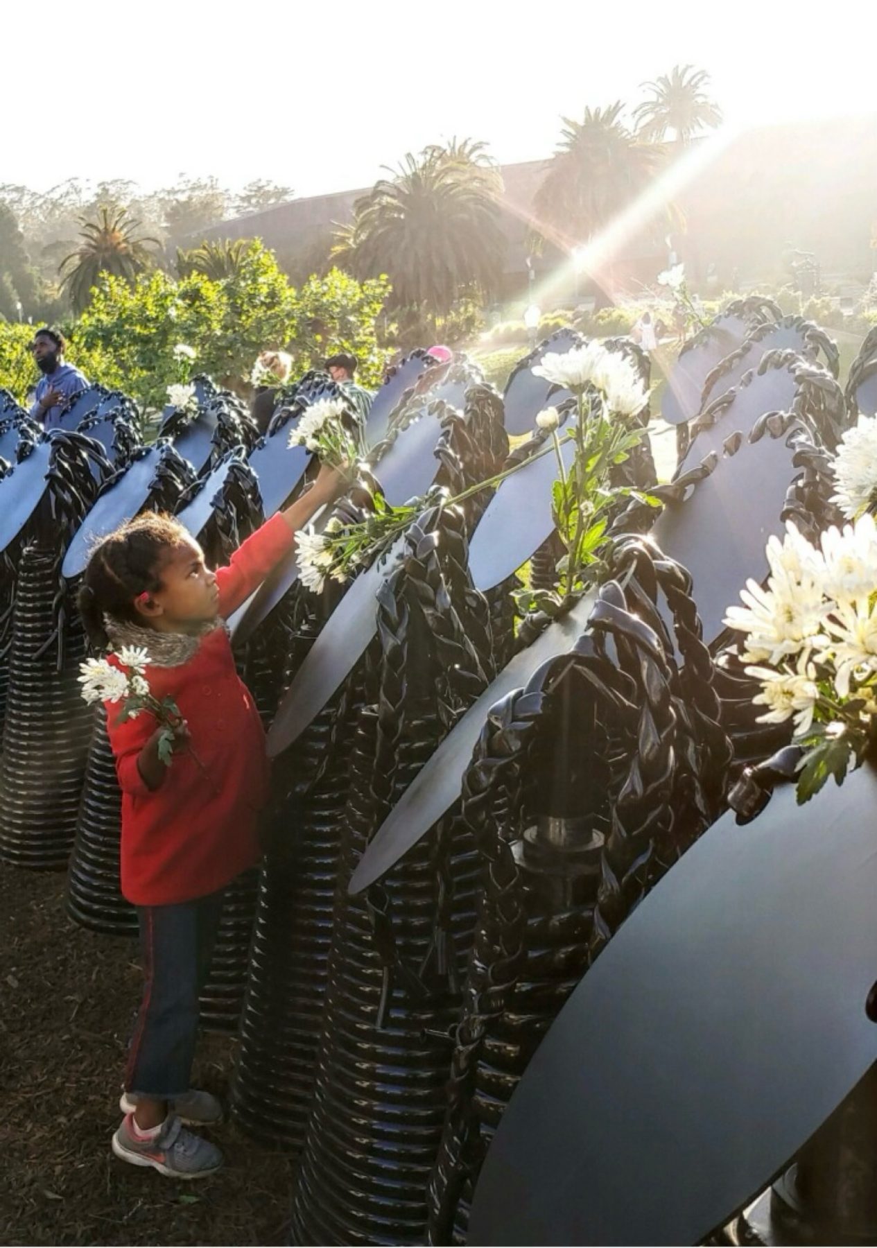Girl placing a flower in the hair of the Ancestors at Monumental Reckoning.